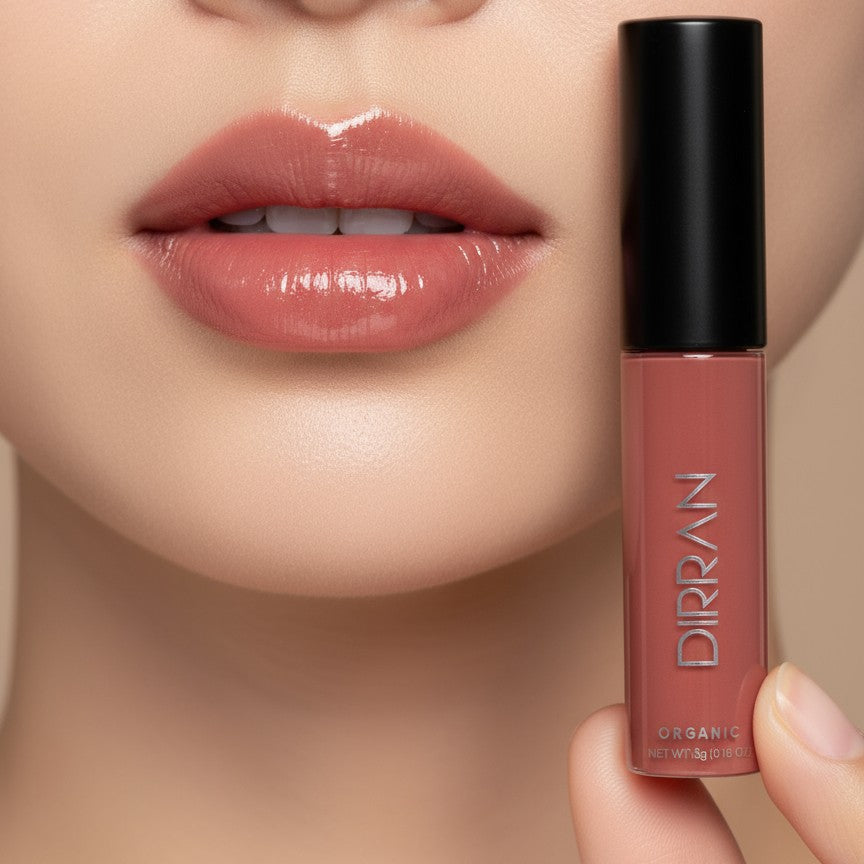 Close-up of glossy natural lips wearing Dirran Organic Natural Lip Gloss in a warm mauve shade, with the lip gloss tube displayed beside the lips.